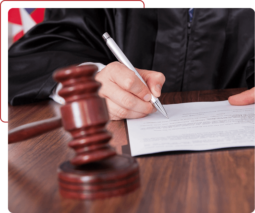 Judge signing a legal document beside a gavel.