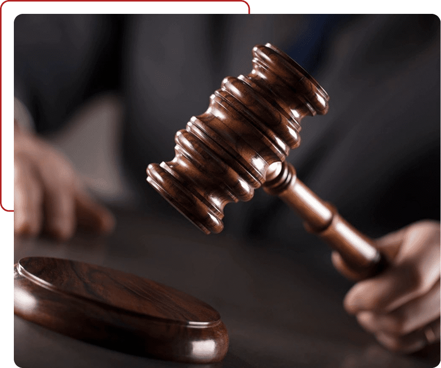 A judge's hand striking a wooden gavel in a courtroom.